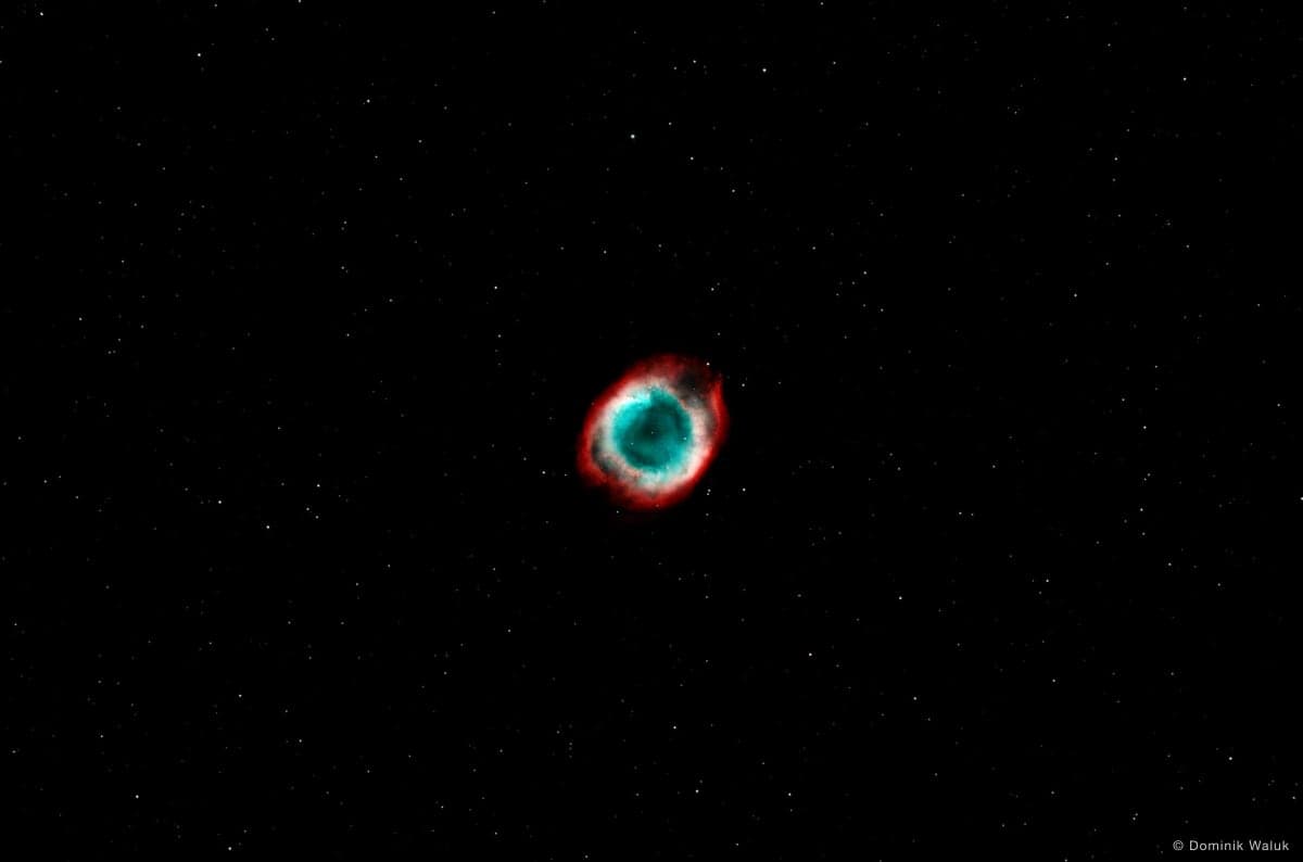 Der Helixnebel: ein rot und blaugrün leuchtender Ring vor einem dunklen Sternenfeld.