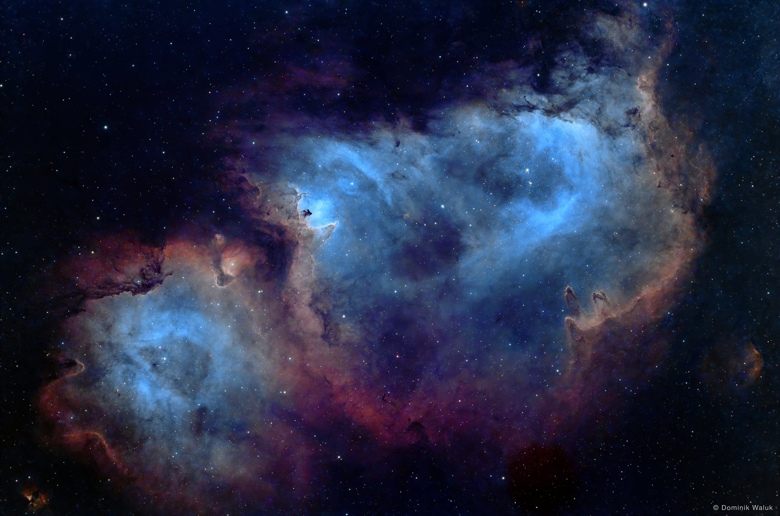 Der Seelennebel: zwei grosse, blau leuchtende Gashöhlen mit rot-goldenen Rändern und dunklen Staubsäulen.