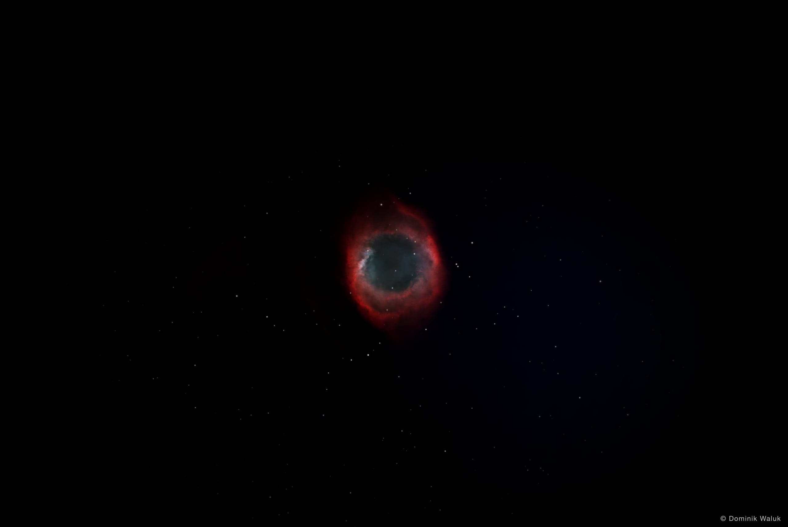 Der Helixnebel: ein rot und blaugrün leuchtender Ring vor einem dunklen Sternenfeld.