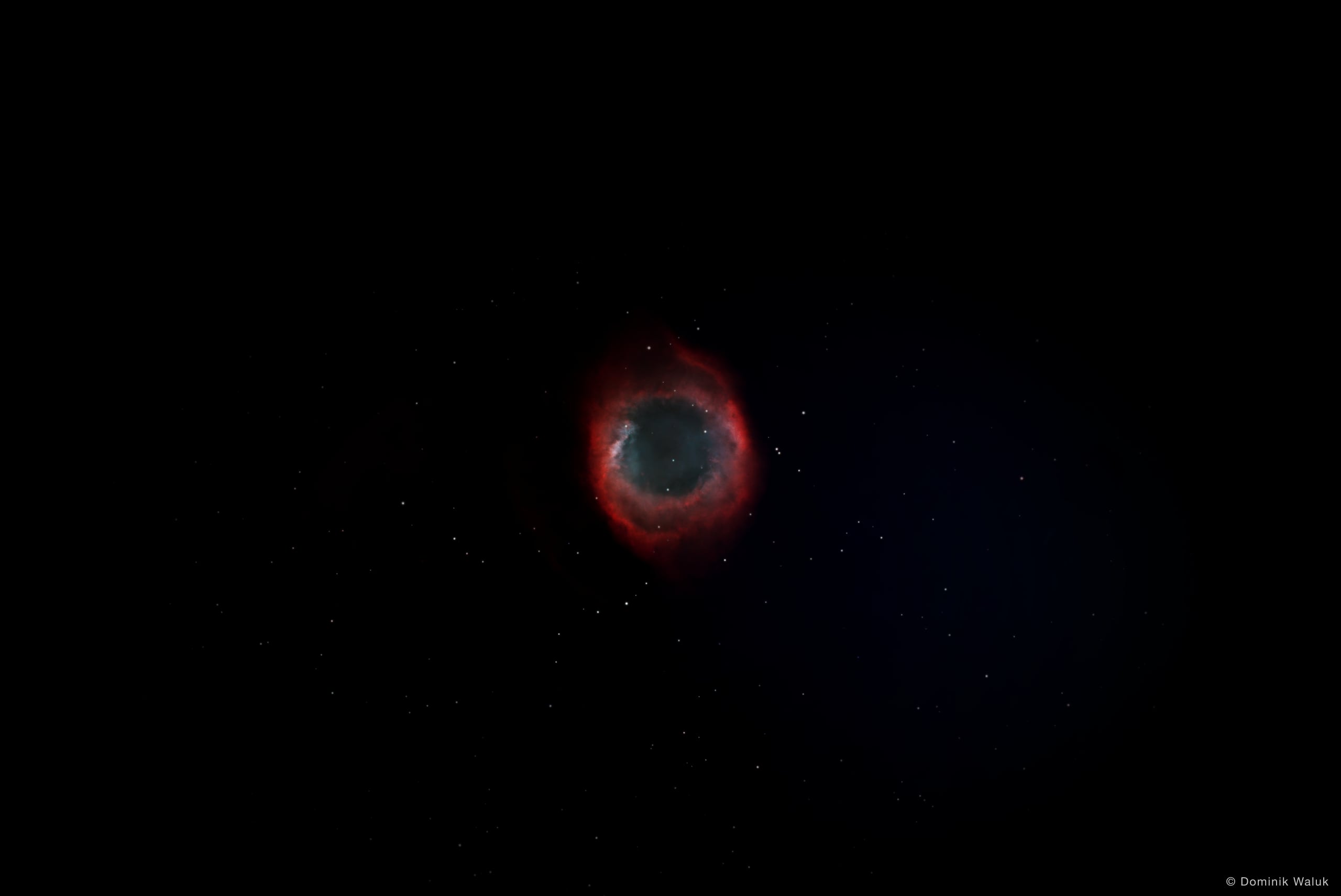 Der Helixnebel: ein rot und blaugrün leuchtender Ring vor einem dunklen Sternenfeld.