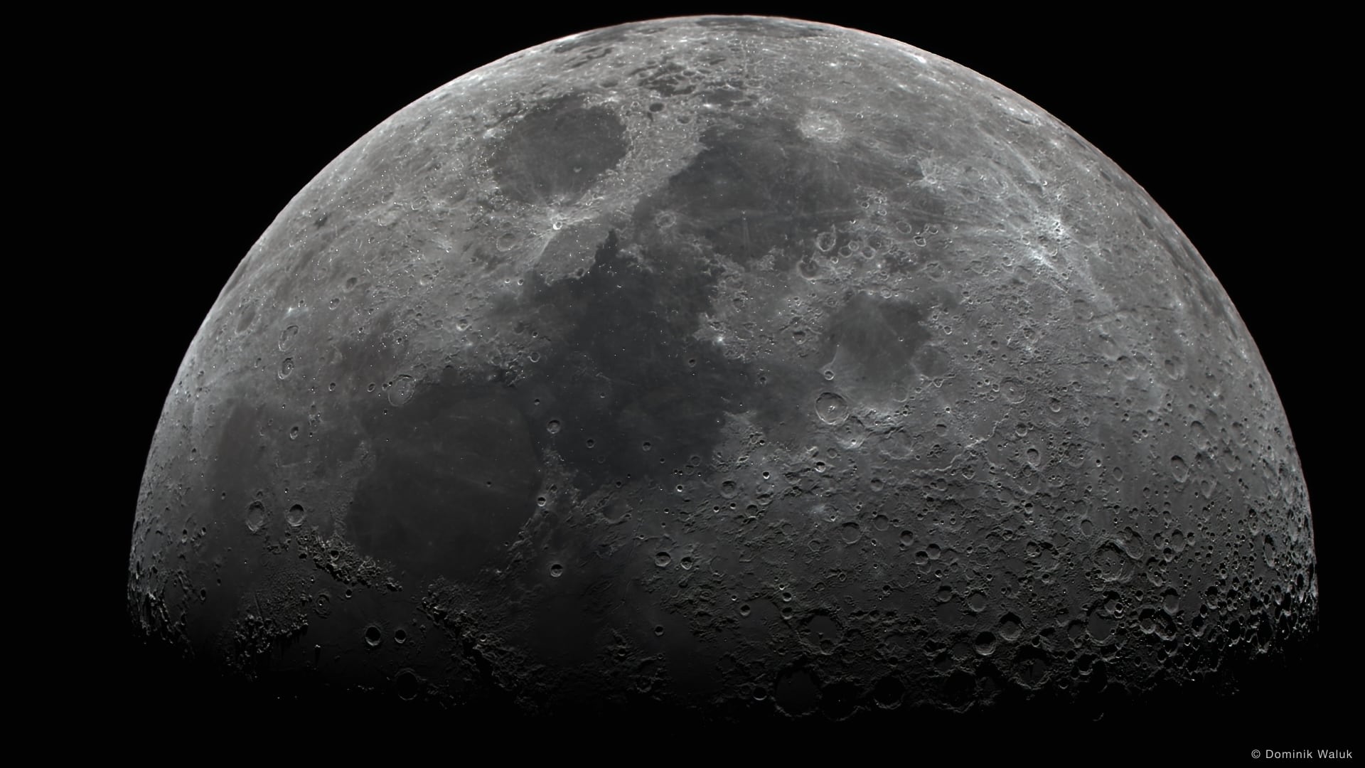Der Mond, zur Hälfte beleuchtet: eine helle Kuppel voller Krater und dunkler Ebenen über schwarzem Grund.
